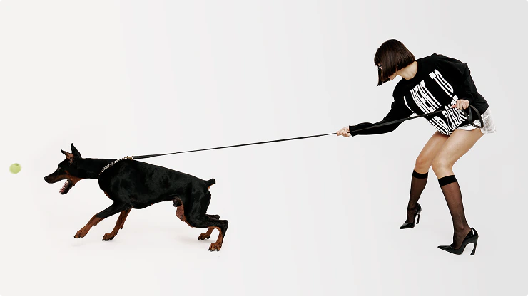 A woman in Court Date apparel playing fetch with a Doberman